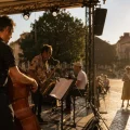 Concert en plein air pendant une canicule avec musiciens sur scène et public cherchant l’ombre