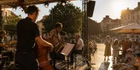 Concert en plein air pendant une canicule avec musiciens sur scène et public cherchant l’ombre